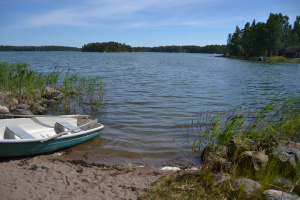 Prästholmens lilla simstrand med roddbåt.